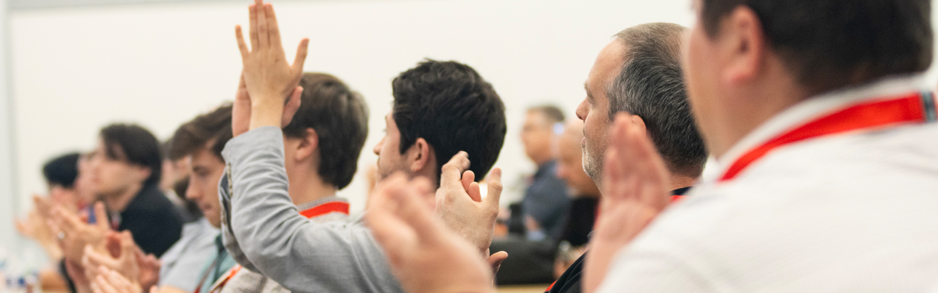 Audience members seated in rows applaud during a presentation.
