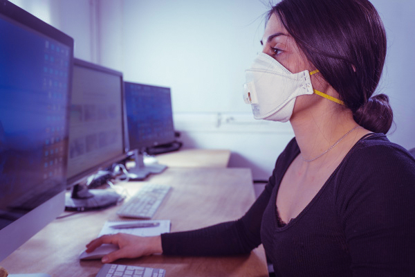 Female student wearing a mask uses computer in computer lab