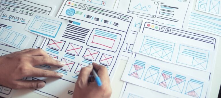 Hands drawing wireframe images of a website in progress