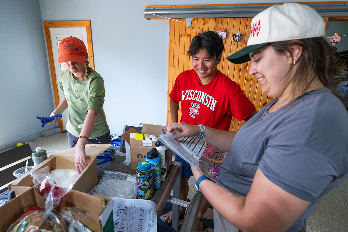 Graduate students in the Water Resources Management program, smile while preparing to test lake water