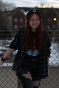 Photo of Lauren Flaschenriem standing in front of a chain link fence with buildings in the background