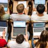 Students sitting in rows of desks with laptops open
