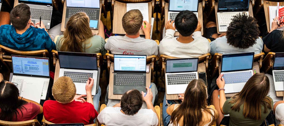 Students sitting in rows of desks with laptops open