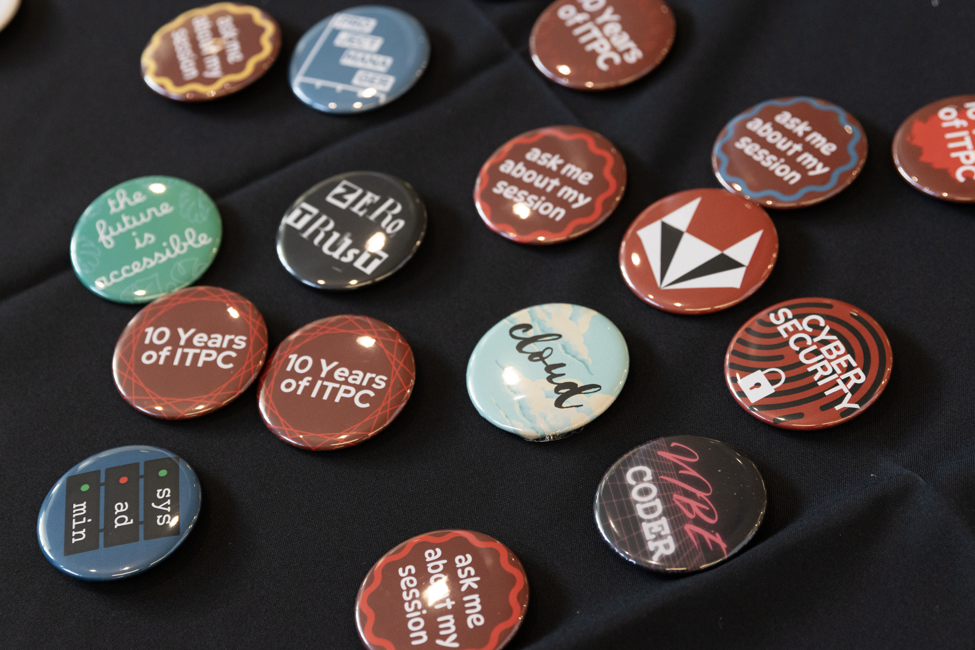 A variety of buttons with IT-themed designs scattered across a table.