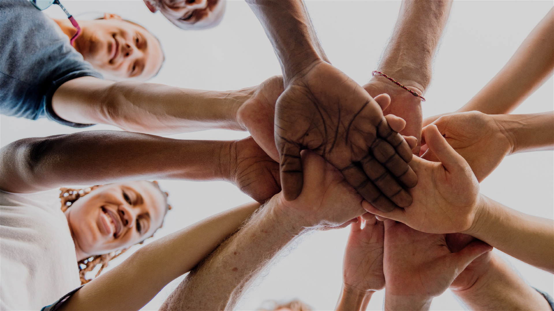 Group of people gathers together and puts their hands in middle of circle