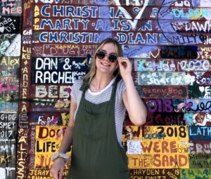 Photo of Kaitlynn Ellis standing in front of a colorful wall