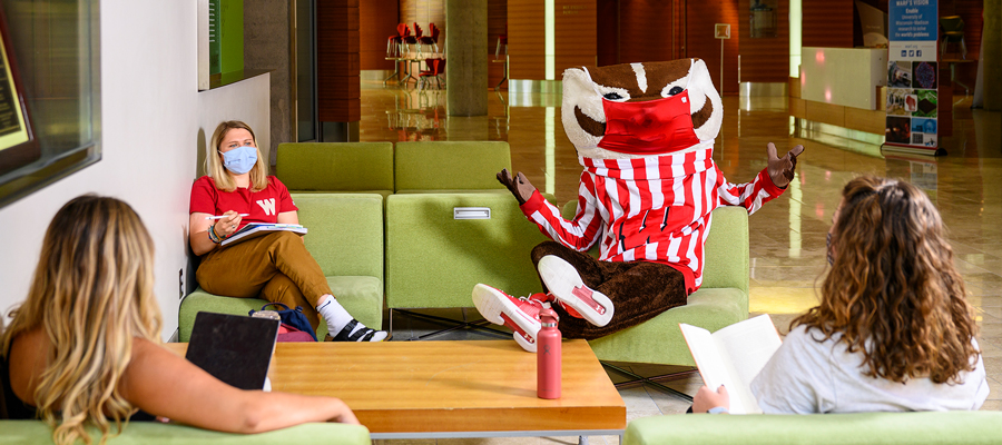 Bucky Badger meets with three students while seated together in the Discovery Building..