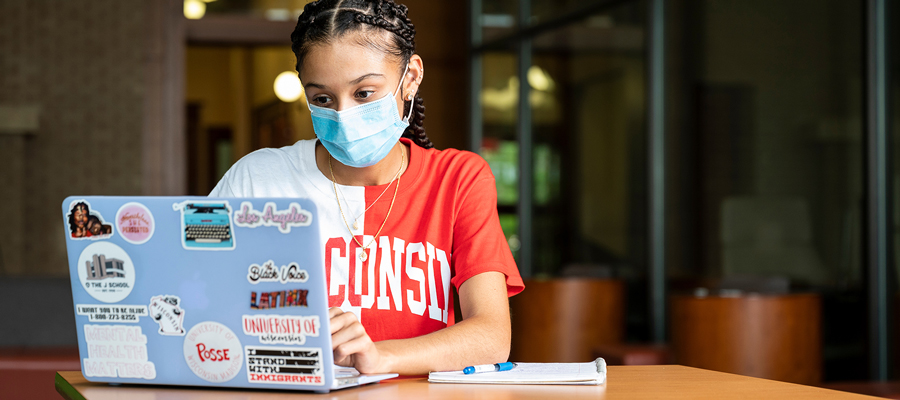 Masked student using laptop