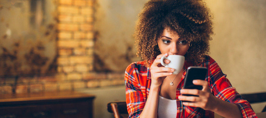 Woman drinking coffee and looking at her phone