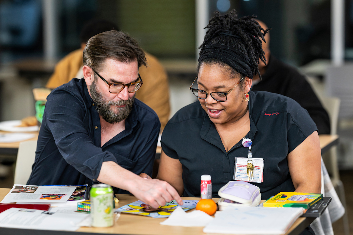 Kevin Mullen, assistant professor in liberal arts and applied studies and director of adult education for the UW Odyssey Project, works with Odyssey Project student during an evening writing class