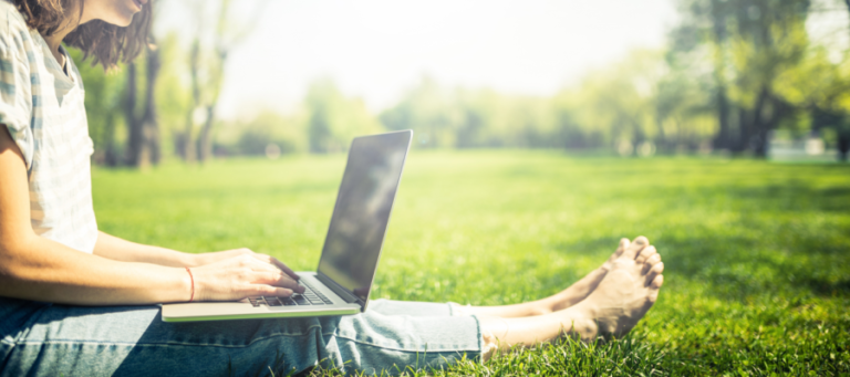 Student with laptop sitting in grass