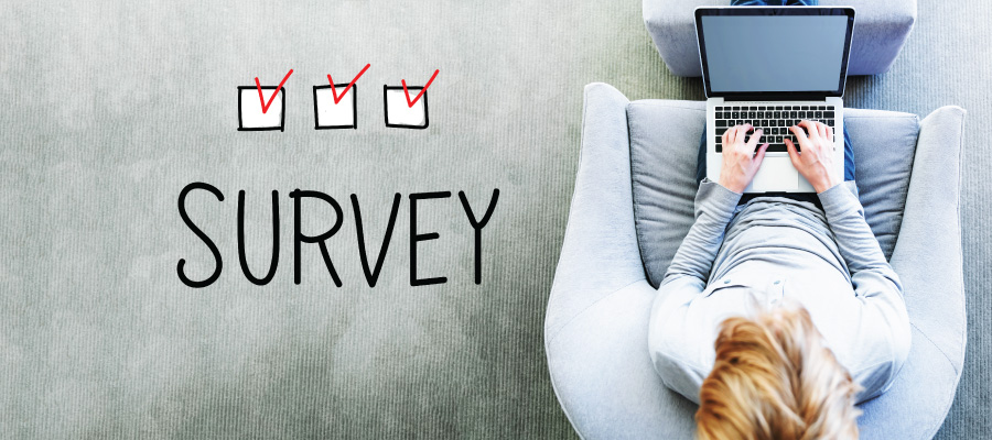 Word "Survey" next to man on laptop computer