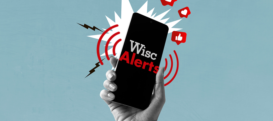 Hand holding a smartphone displaying "Wisc Alerts" with red alert waves and social icons.