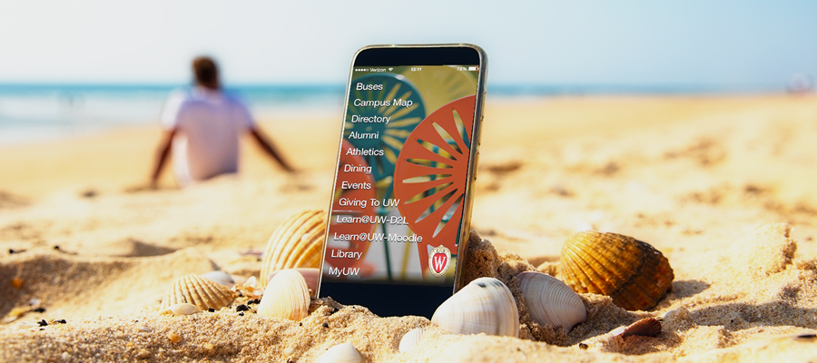 A smart phone on the beach with the Wisconsin app on the screen.