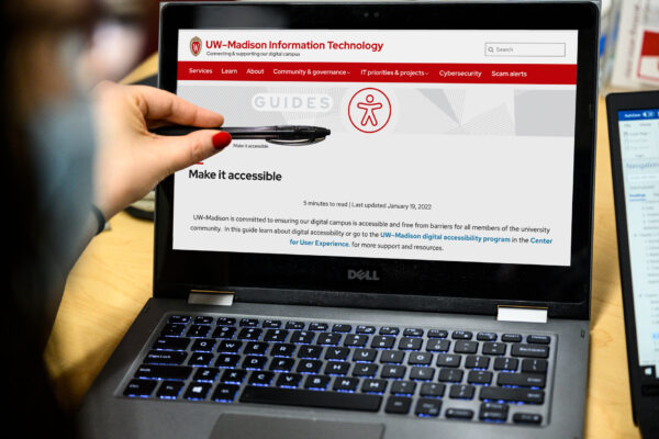 A person pointing at a laptop screen with the "Make It Accessible" guide.