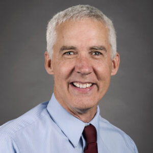 Paul Oliphant wearing a light blue dress shirt and a maroon neck tie